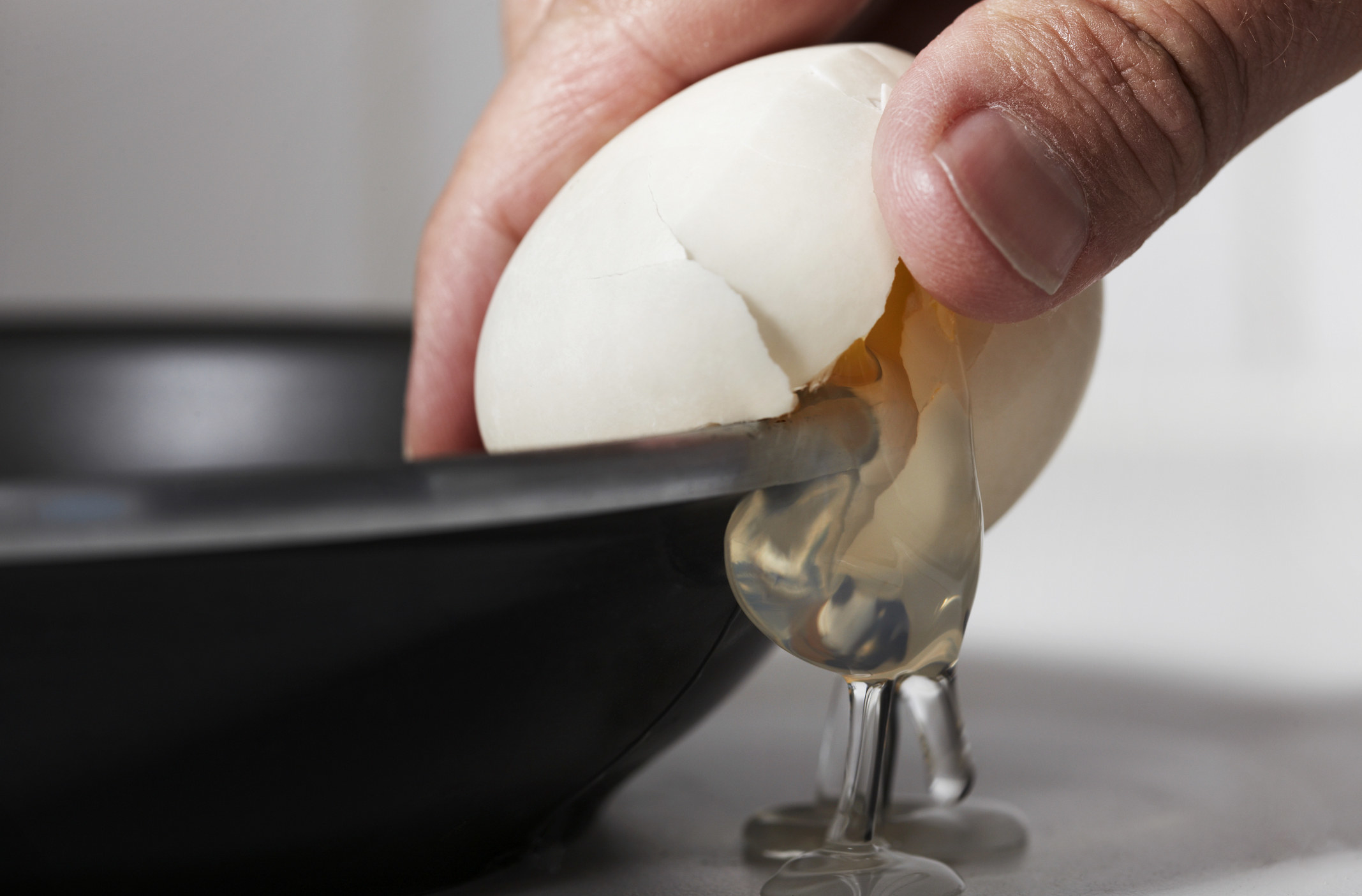 hand cracking an egg against a pan
