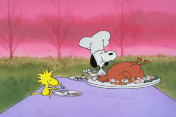 Snoopy and Woodstock sit at an outdoor table and eat turkey together on Thanksgiving