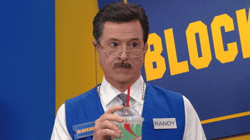 Stephen Colbert dressed as a Blockbuster employee named Randy sipping on a Big Gulp