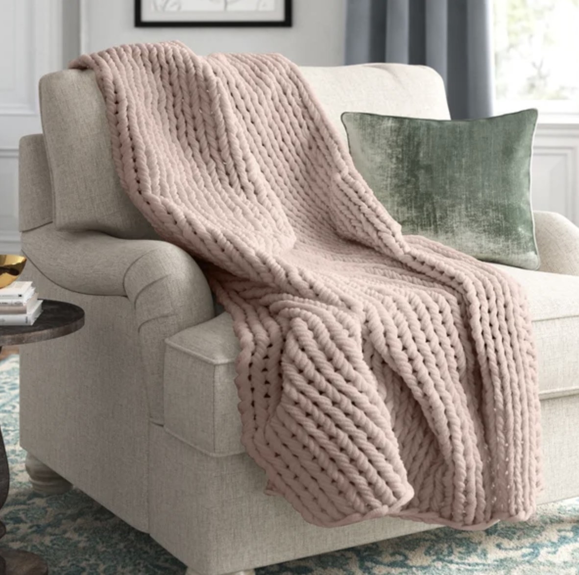 The pale pink blanket is hung against a chair