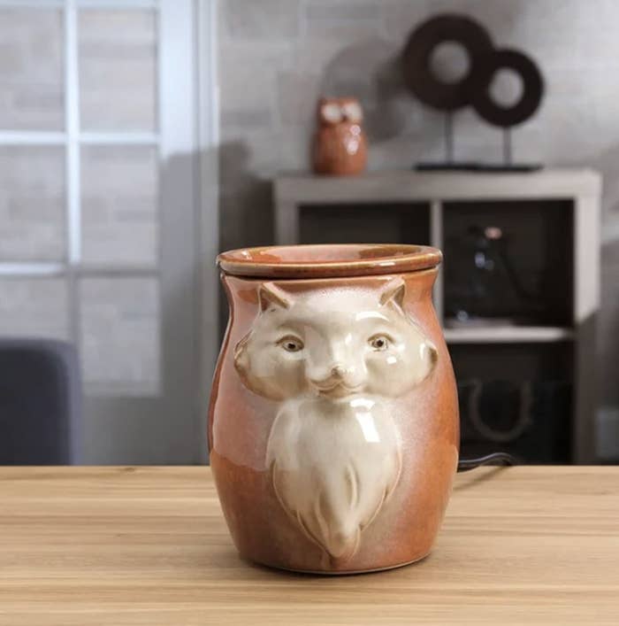 The kitty porcelain warmer has a terracotta and cream color scheme