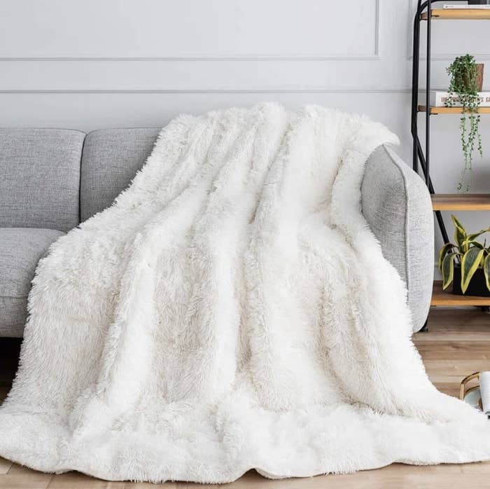 The bright fluffy white blanket is draped over a couch