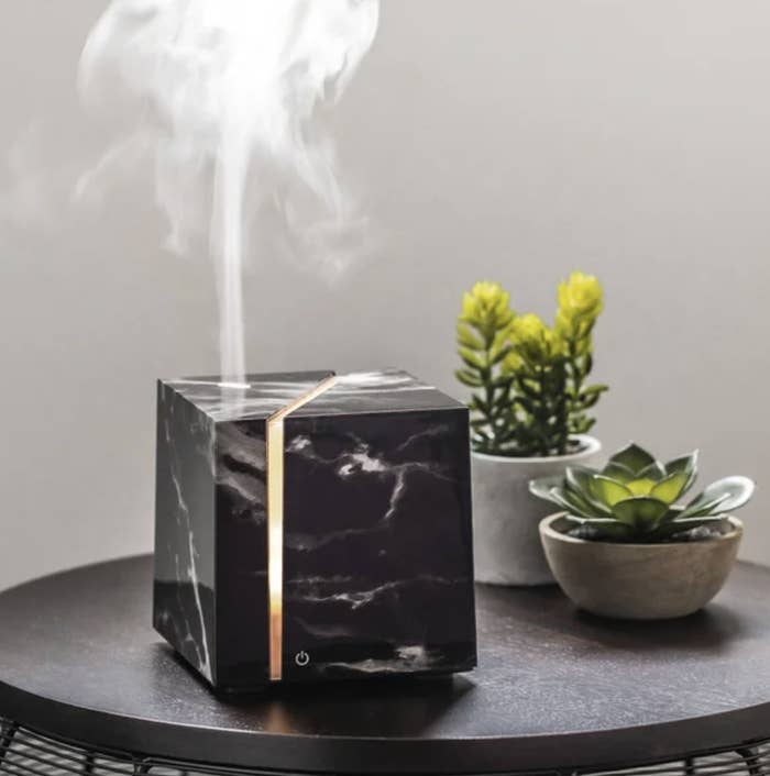 The black oil diffuser has a marble-like texture and warm orange light