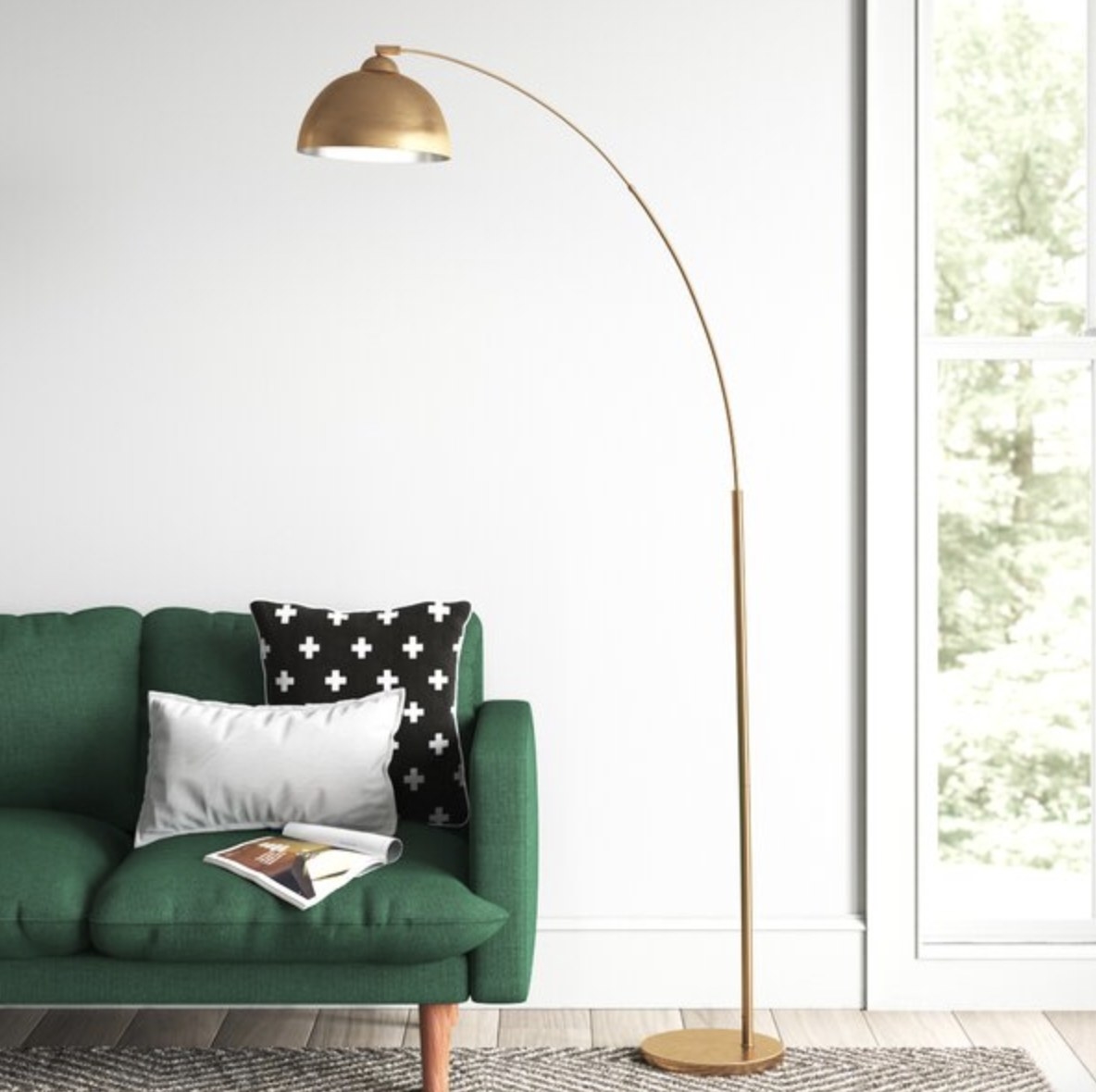 The arching gold lamp is tall and curving over a green couch