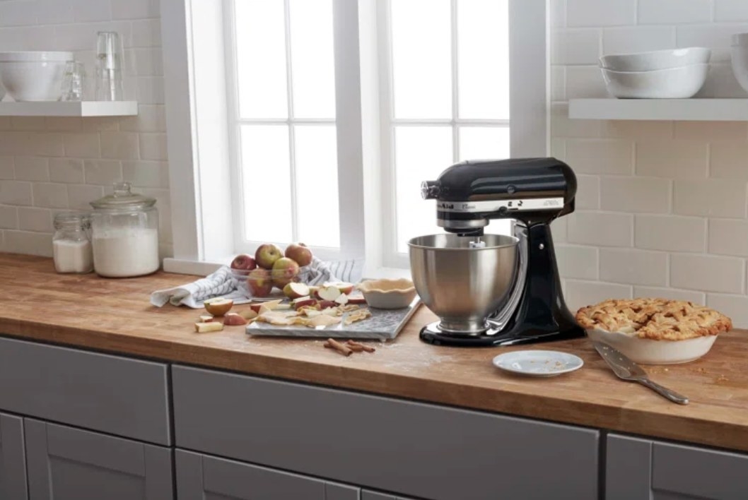The kitchen has a black stand mixer and is surrounded by apple pie ingredients