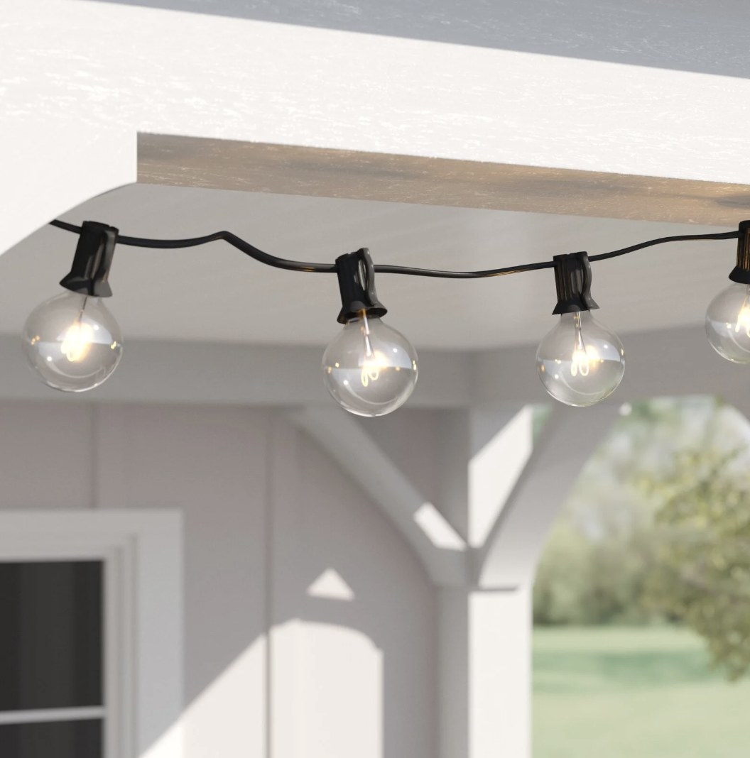 The black string lights are hung outside near a white structure