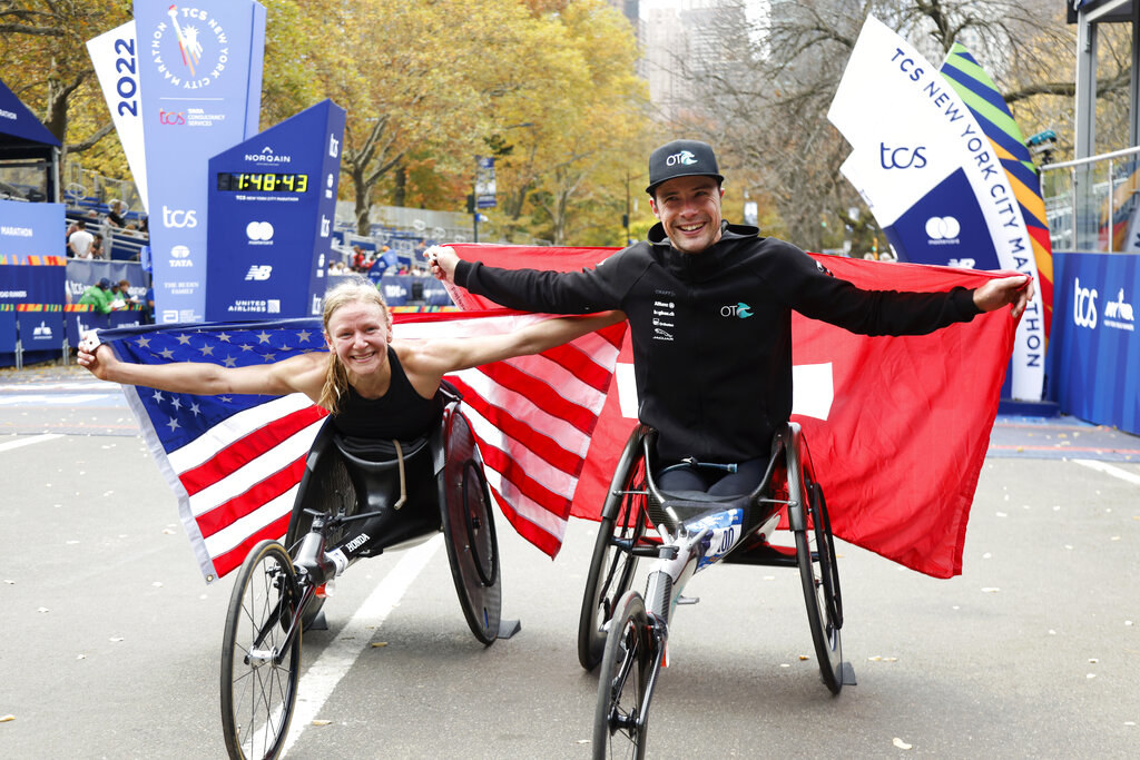 Susannah holds a US flag and Marcel holds a Swiss flag