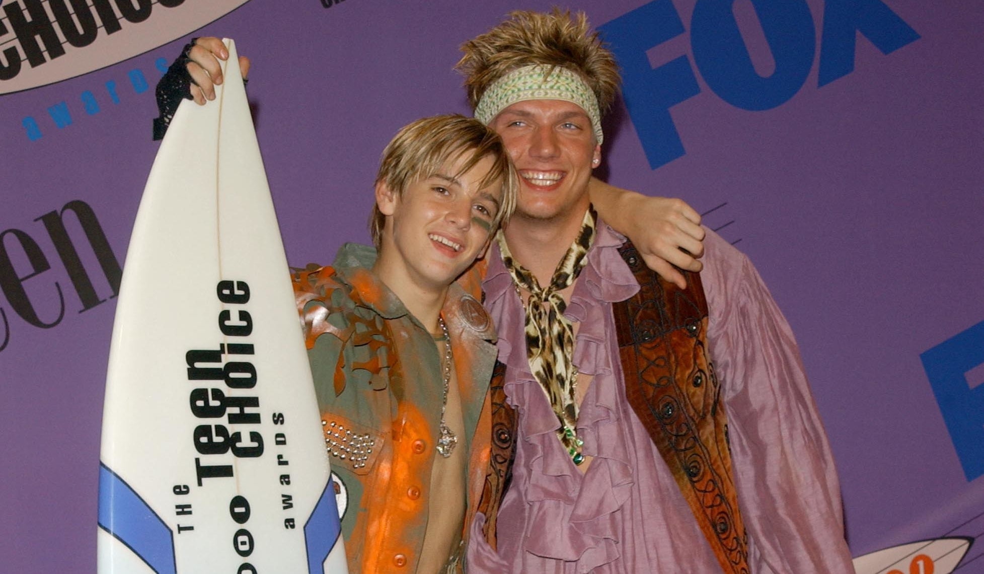 Aaron has his arm around Nick's shoulder as both of them smile