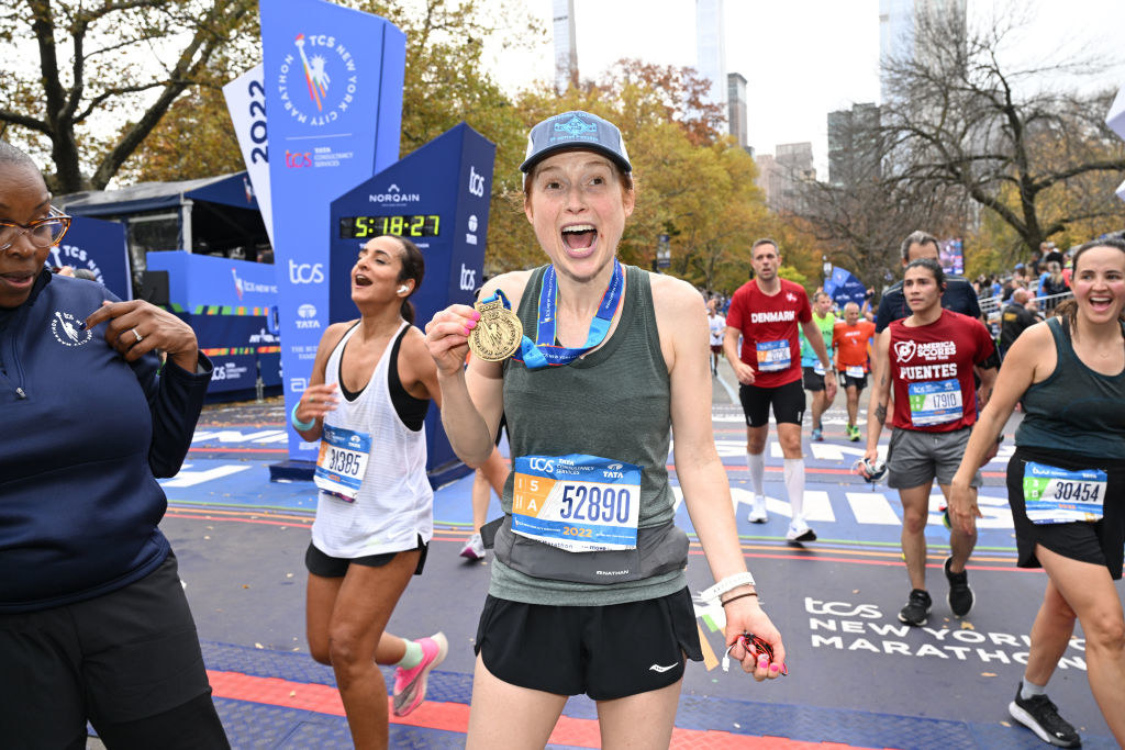 The actor holding up a medal at the finish line