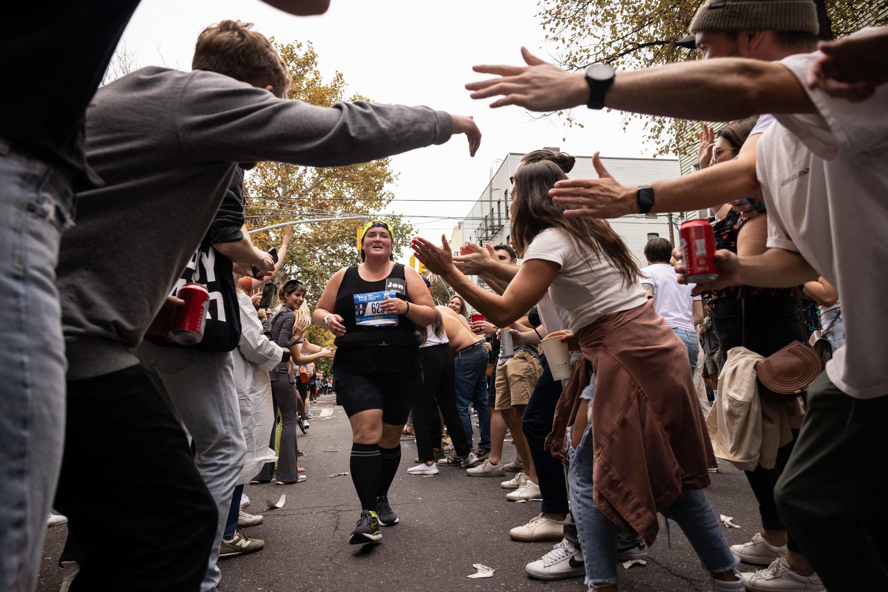 Runners move through a narrow lane amid applauding spectators