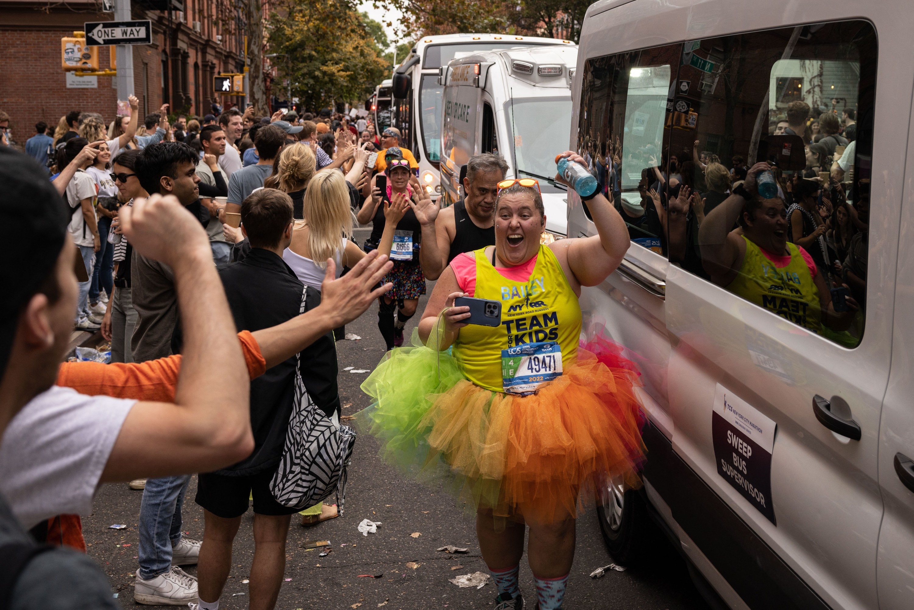A runner in a multicolored ballet tutu holds up their arm