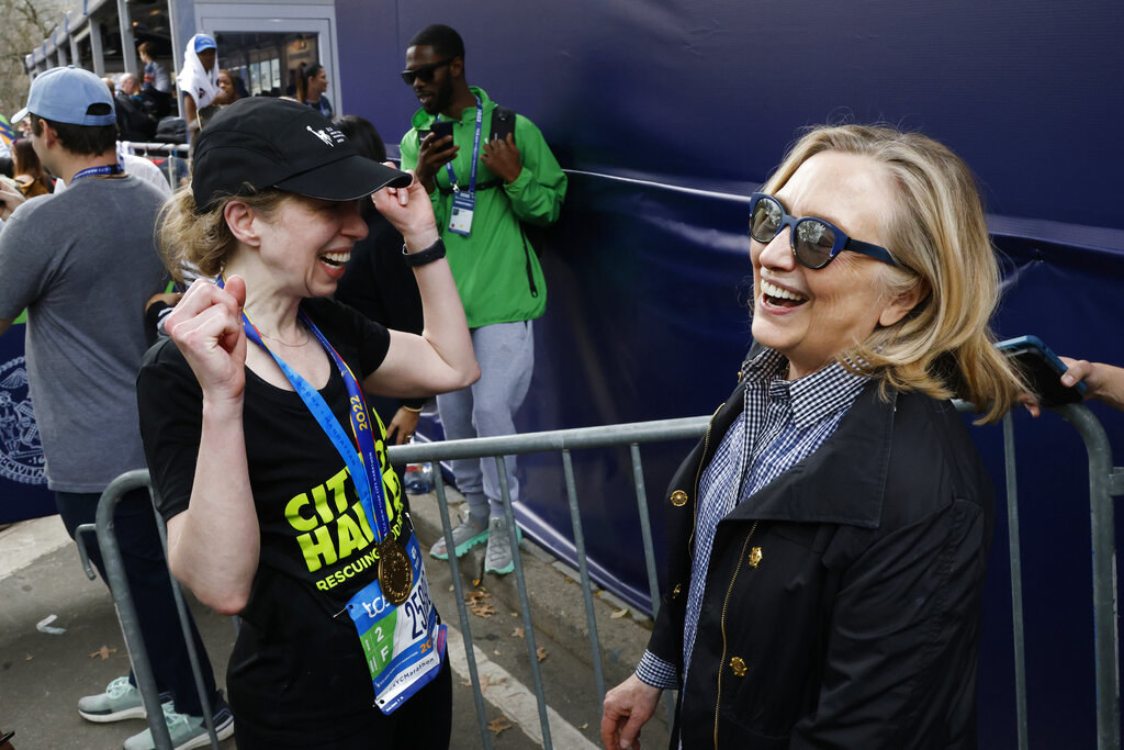 Chelsea wearing a hat and holding up her arms as she smiles at her smiling mother