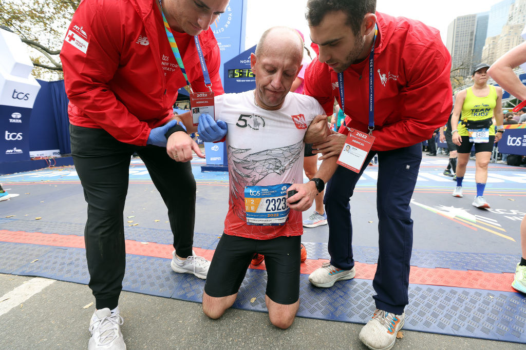 A man on his knees being held by two people