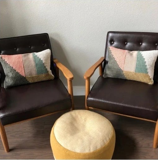 Two of the pillows on matching brown leather chairs with an ottoman in the middle