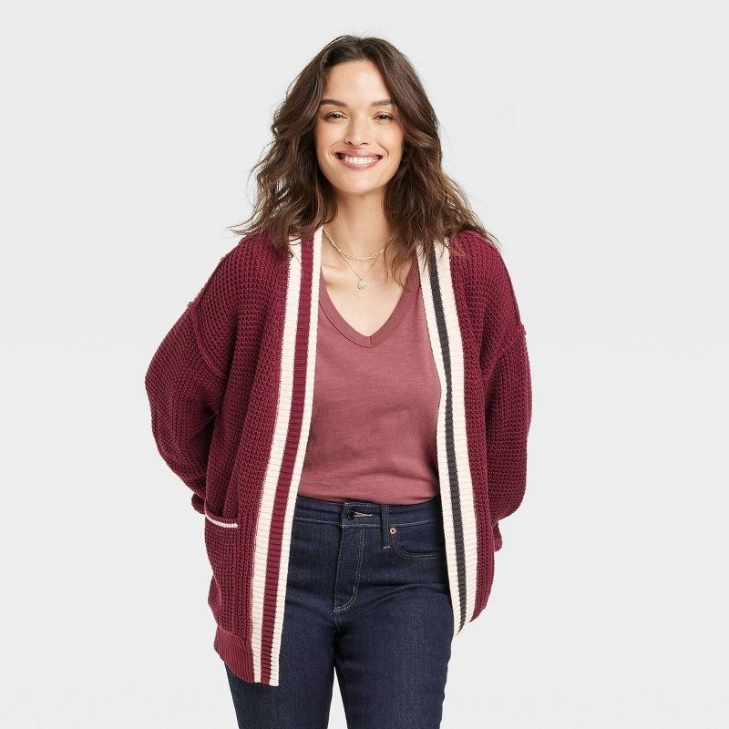 model wearing maroon open-front cardigan with white stripes on the lapel