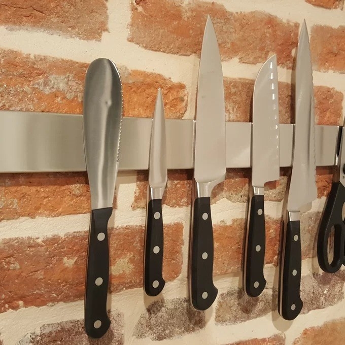 The magnet against a red brick wall with six knives