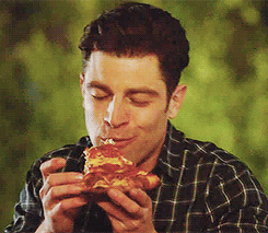A gif of Schmidt from New Girl excitedly eating a pizza