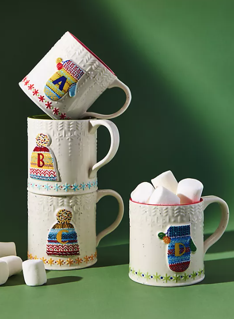 three mugs with either a mitten or a pom hat on it and an initial in the middle