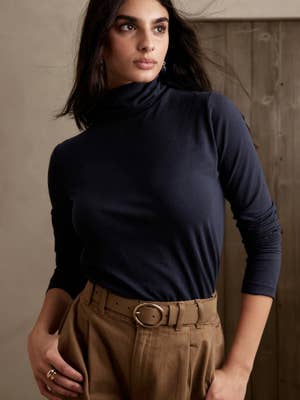 model wearing a navy turtleneck with tan pants