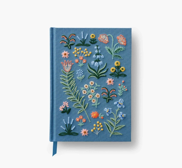 a blue journal with embroidered flowers on the cover