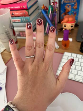 buzzfeed editor's hand with red nails and silver glitter polish on top