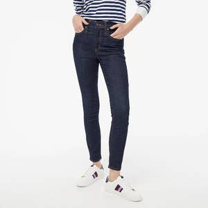 model wearing high-waisted skinny jeans in a dark wash with a striped top and white sneakers