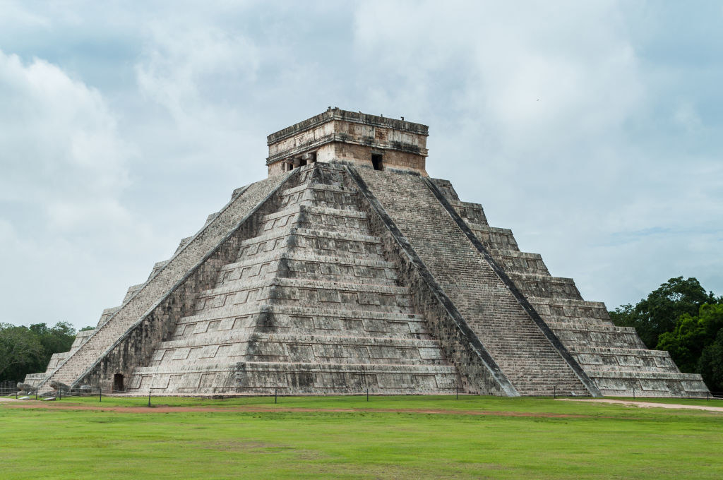 A temple at the top of stairs with maintained grass at the base