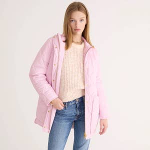 model wearing a light pink puffer coat over a pink sweater with jeans