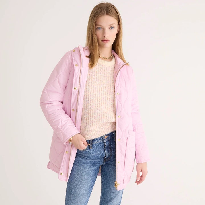 model wearing a light pink puffer coat over a pink sweater with jeans