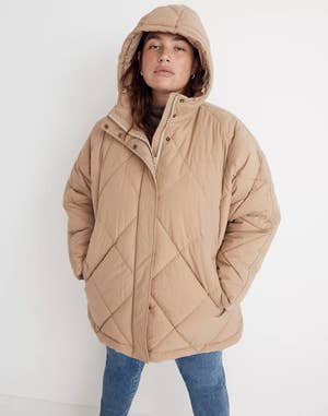 model wearing a beige puffer coat with jeans