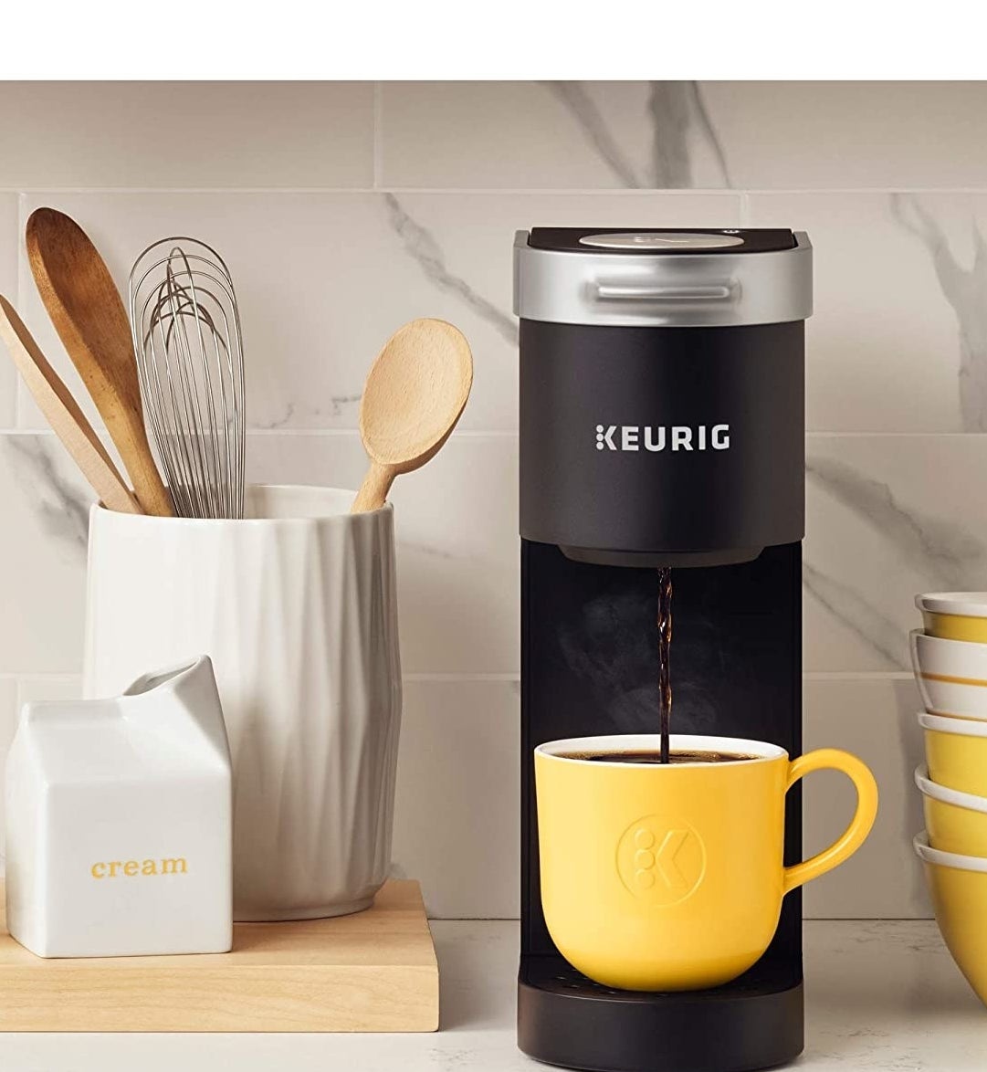 the black k-mini coffee maker pouring coffee into a yellow mug