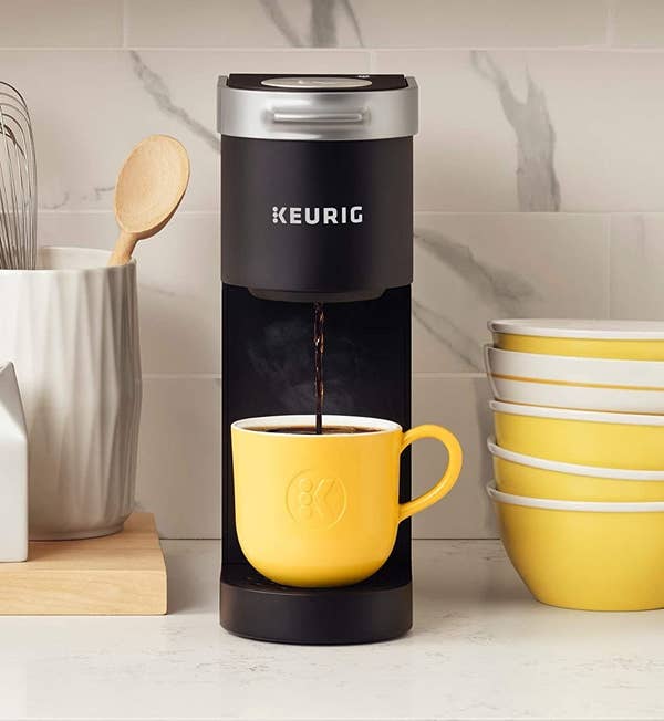 the black k-mini coffee maker pouring coffee into a yellow mug