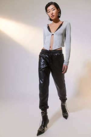 model wearing black faux leather joggers with a silver sweater and black boots