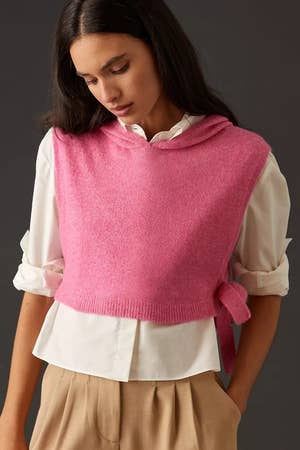 model wearing a pink cropped sweater vest over a white top with tan pants