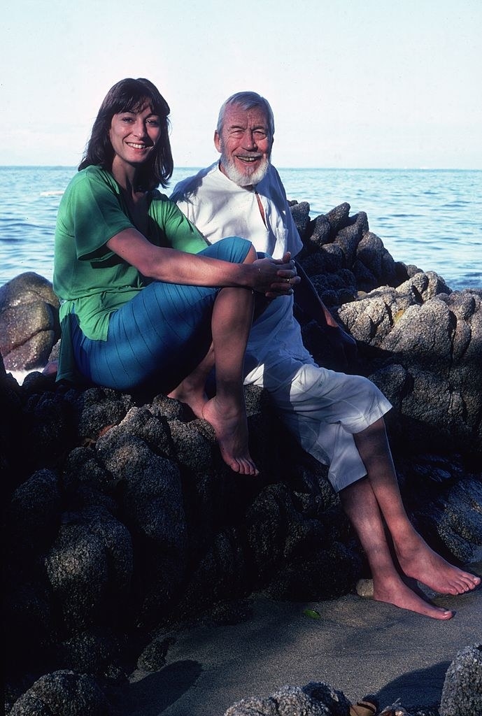 Anjelica and John sitting on rocks on the beach