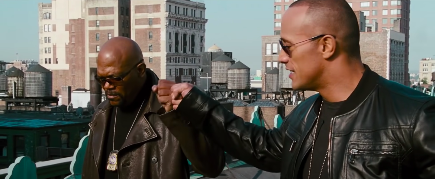 Two men fist bumping on the top of a building