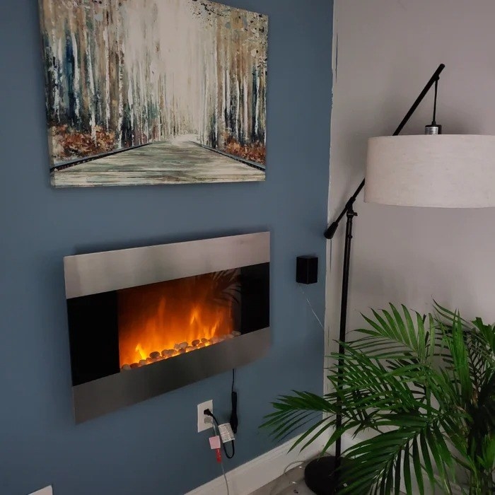 the lit fireplace mounted to a blue wall with an abstract painting above