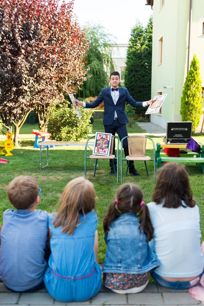 Image of 4 children watching a magic show at birthday party in backyard