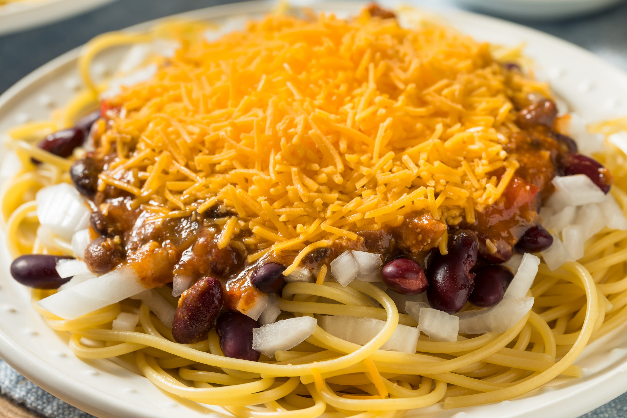 Pasta topped with onions, chili, and cheese