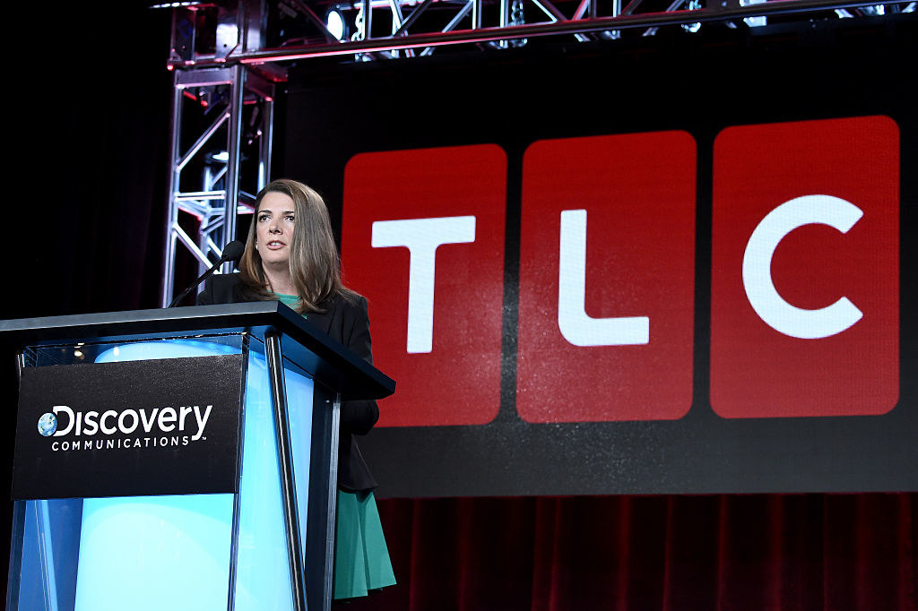 woman speaking at a podium with the TLC logo posted behind