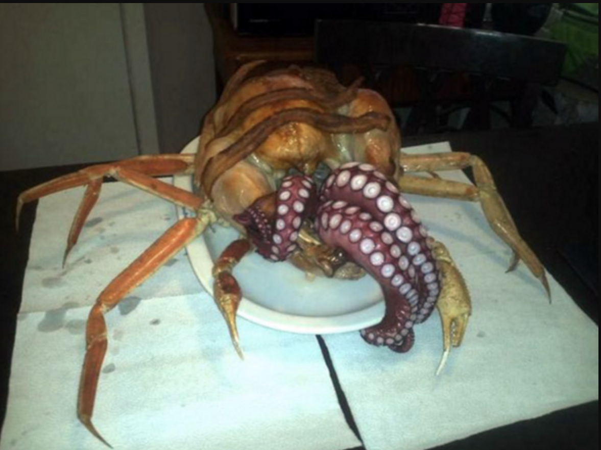 turkey covered with bacon, stuffed with octopus and sitting on top of large crab legs; the tentacles of the octopus are coming out of the turkey, making it look like a monster