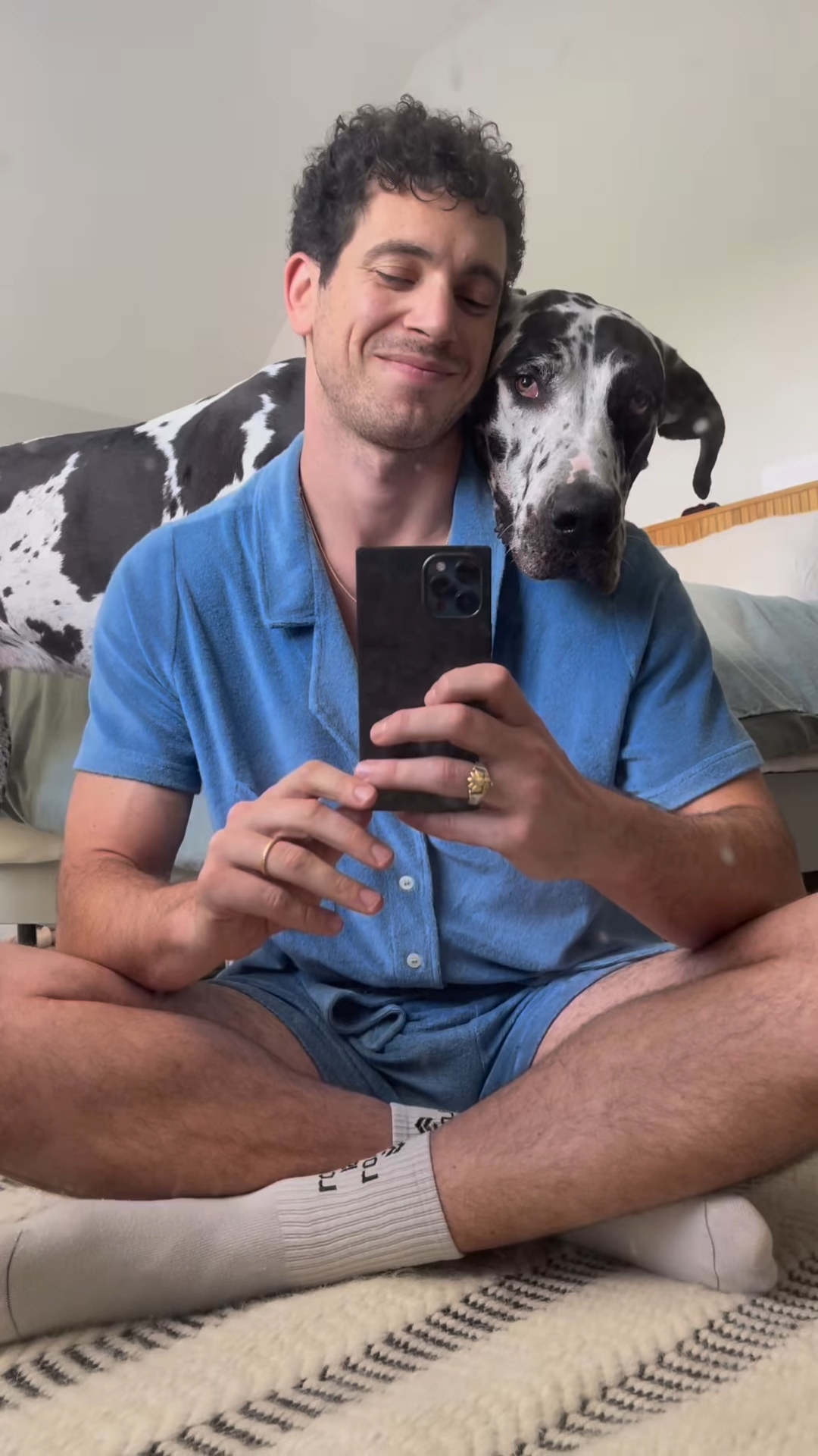 Abe smiling and holding his phone as his dog leans against him