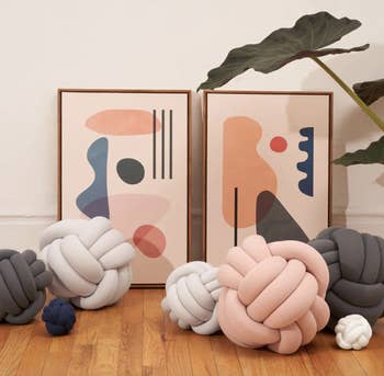 a variety of knotted pillows arranged on a wood floor