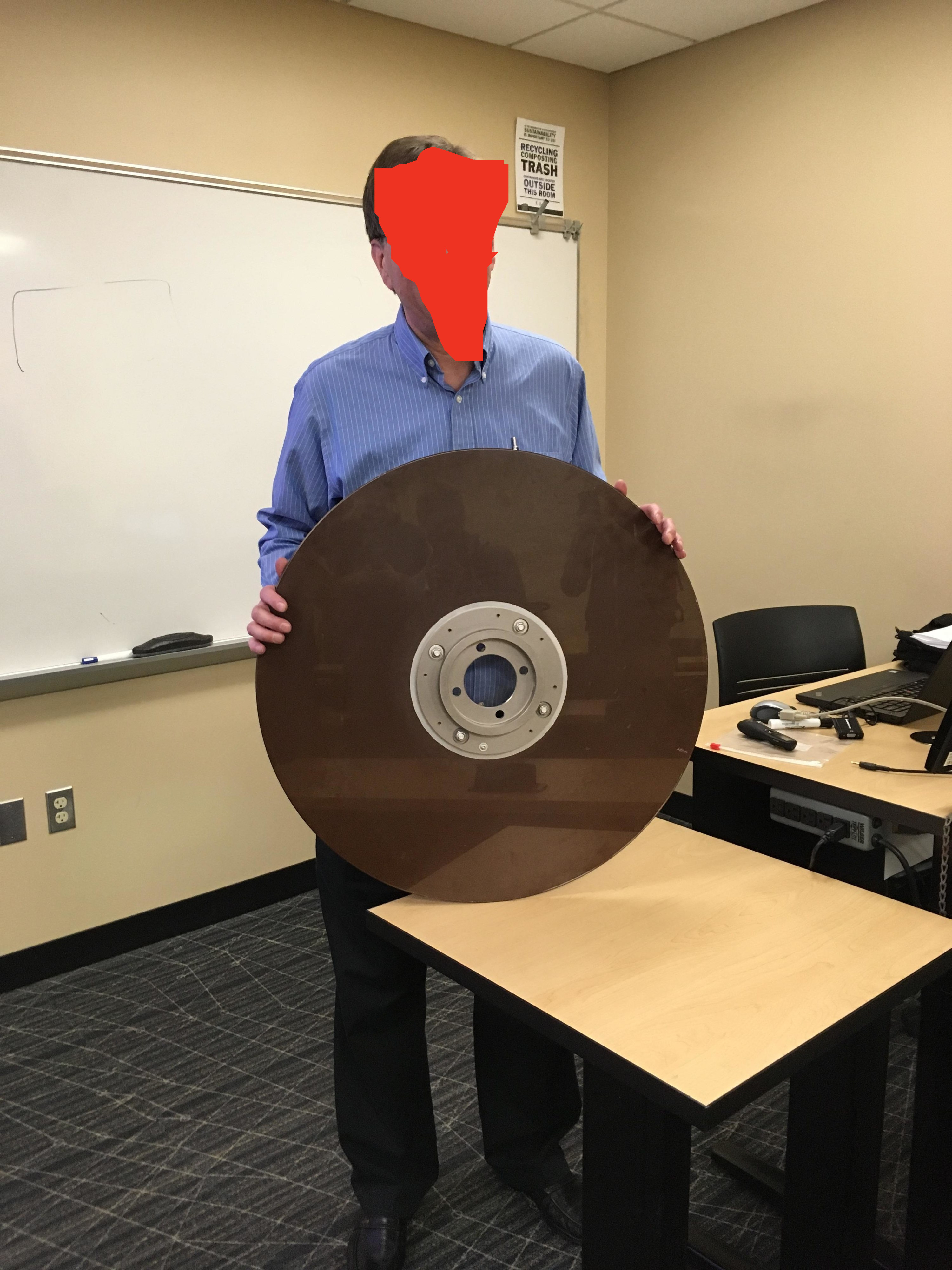 A man holding a disc whose diameter is wider than his torso