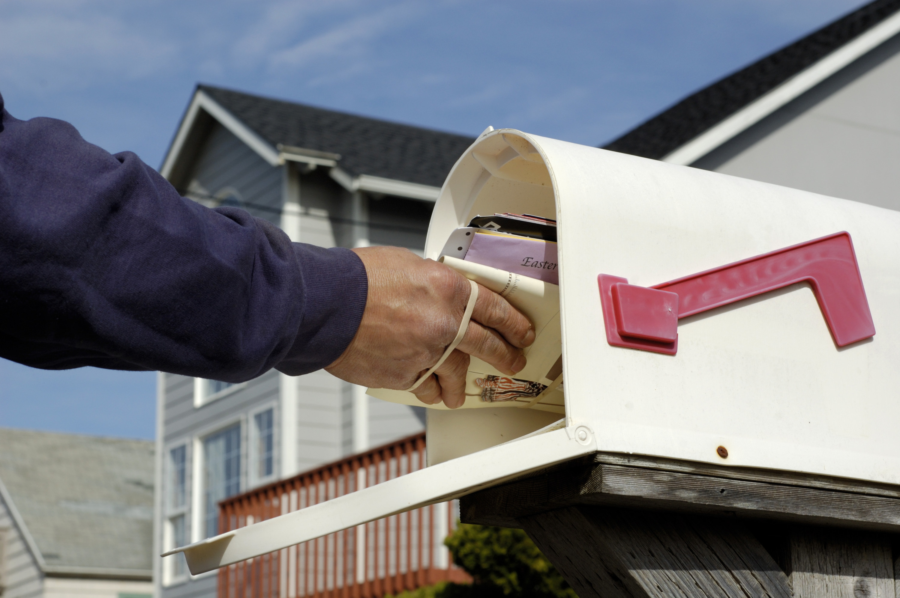 hands putting mail in the mailbox