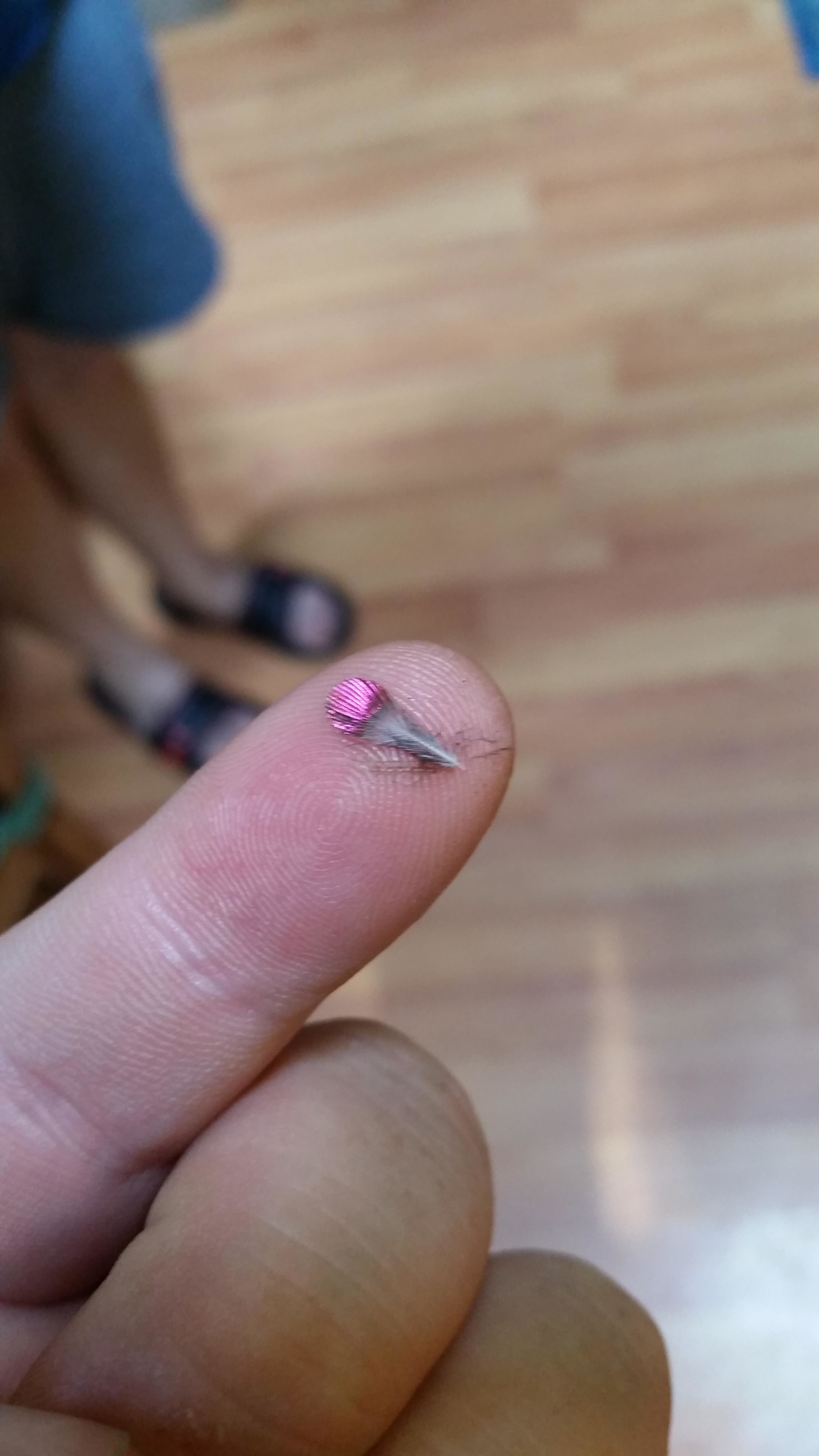 A tiny feather resting on someone&#x27;s pointy finger