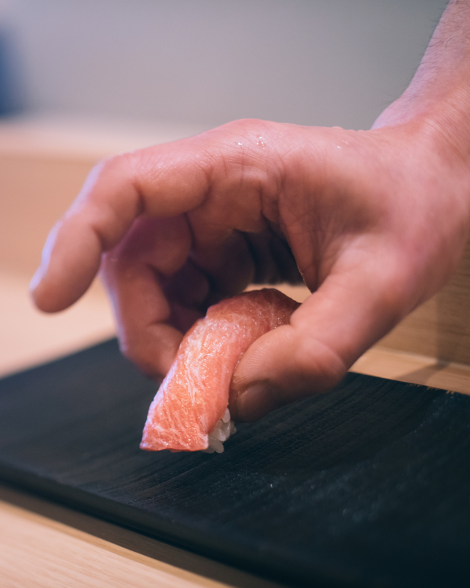 A sushi chef plating a piece of nigiri