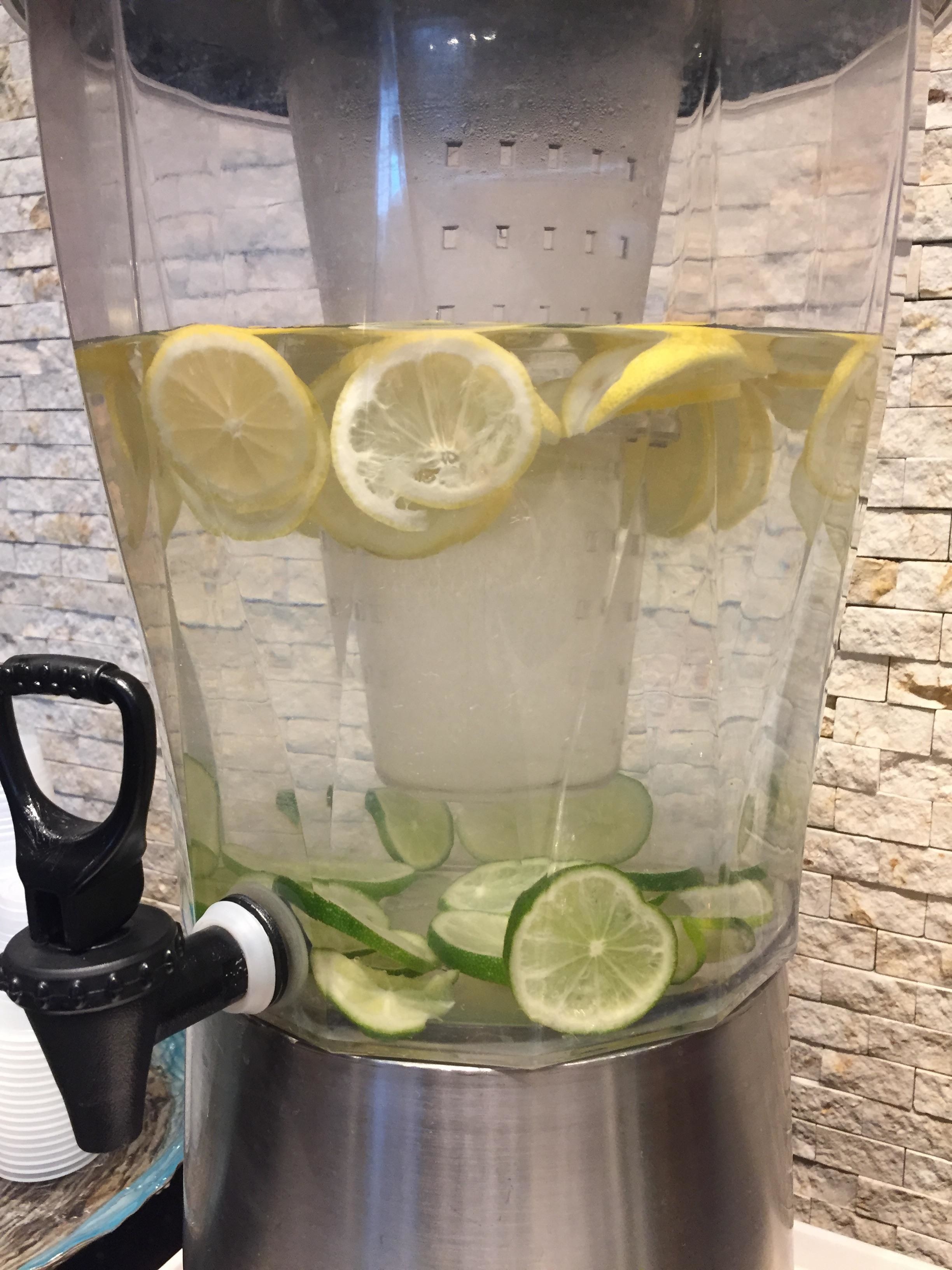 A pitcher of water with slices of lime at the bottom and lemon slices floating at the top