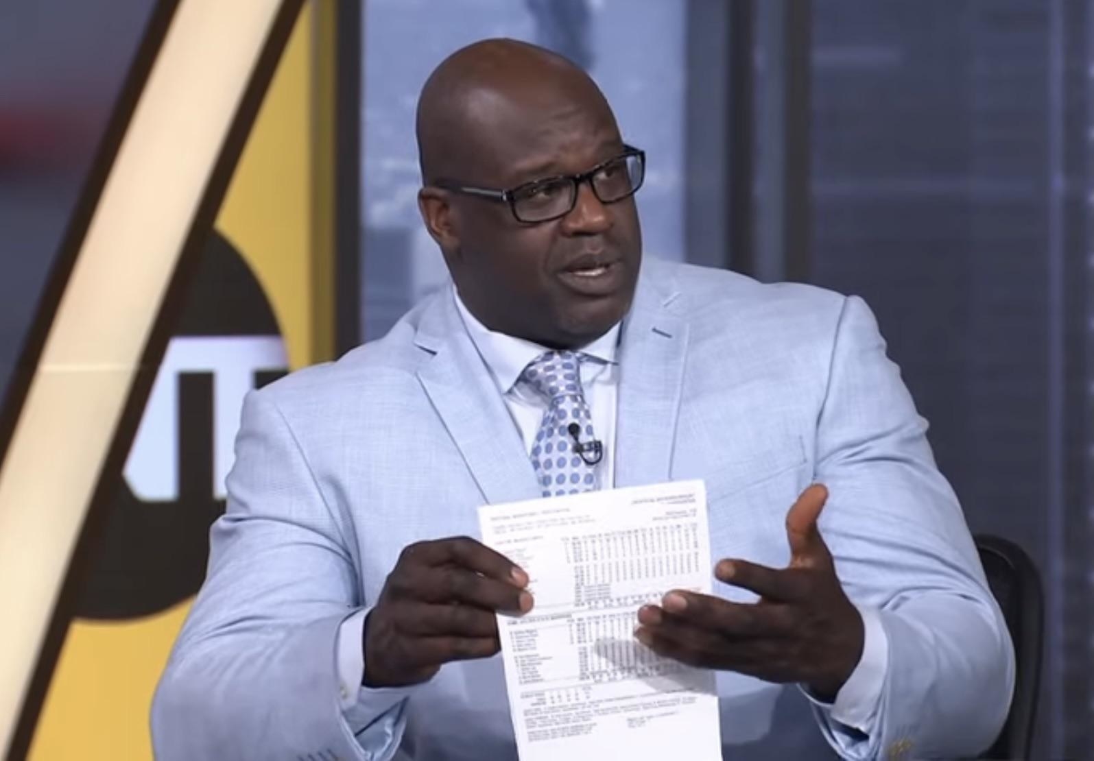 Shaquille O&#x27;Neal in a suit holding a piece of paper
