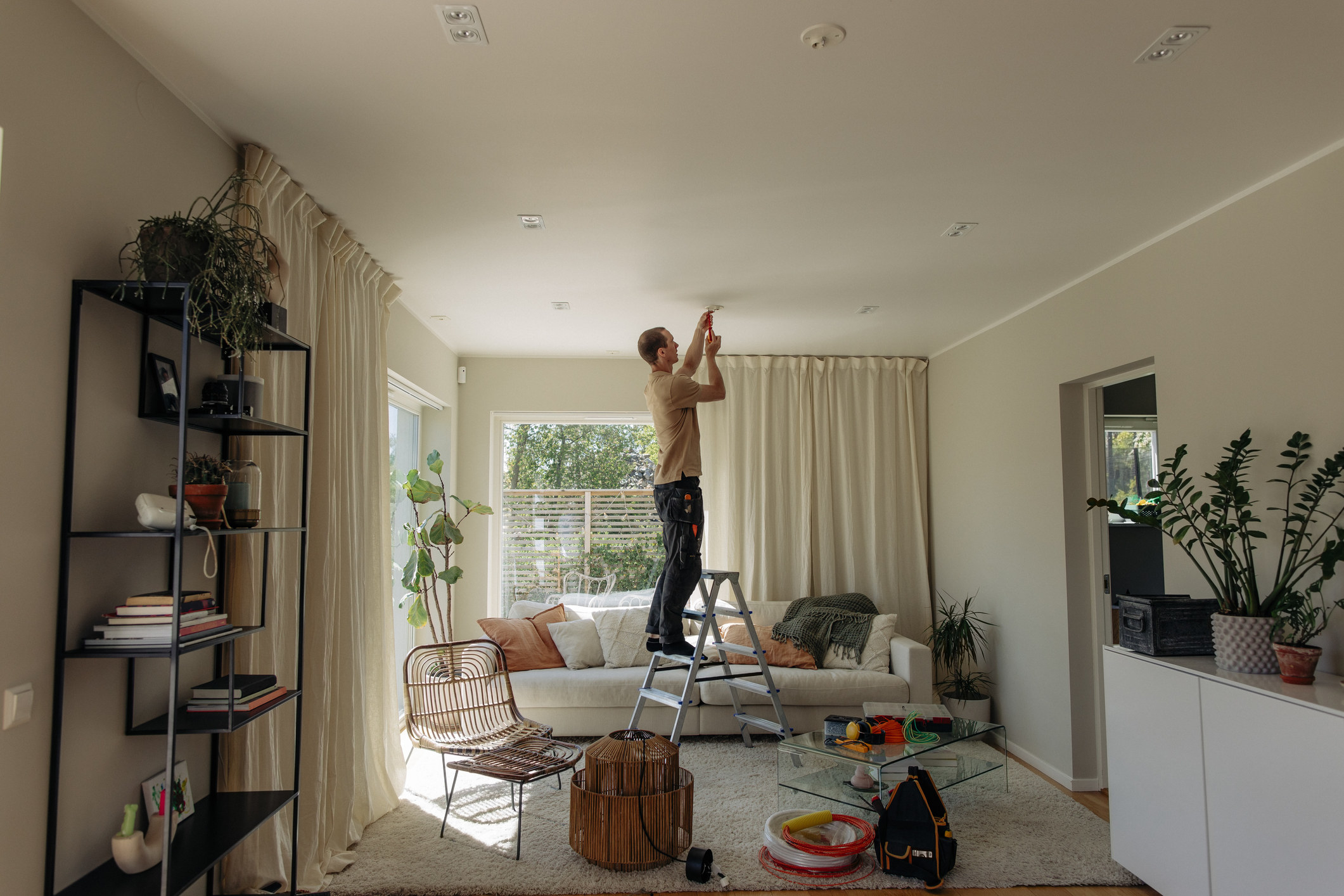 man on a ladder fixing ceiling lights